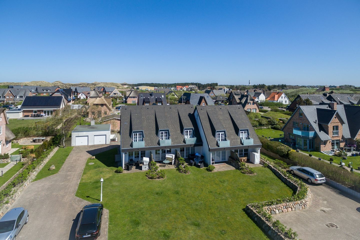 A large, modern house with a spacious front yard and multiple garages.