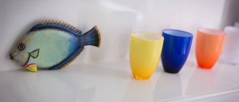 A fish-shaped object on a white surface with four colorful cups beside it.