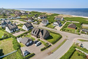 Eine Vogelperspektive eines Küstenwohngebiets mit Häusern, einer Straße und einem Strand im Hintergrund.