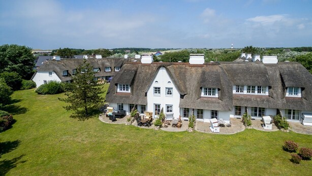 A large, white building with multiple rooms, surrounded by a well-maintained lawn and trees. - Ameland, App. 12 - Charme & Luxus Zwischen Dorfteich und Golfplatz (Wenningstedt-Braderup (Sylt))