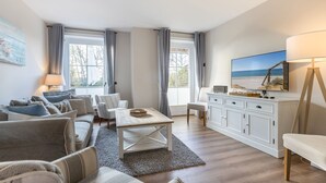 A modern living room with a sofa set, a coffee table, a TV, and a cabinet. - Ameland, App. 12 - Charme & Luxus Zwischen Dorfteich und Golfplatz (Wenningstedt-Braderup (Sylt))