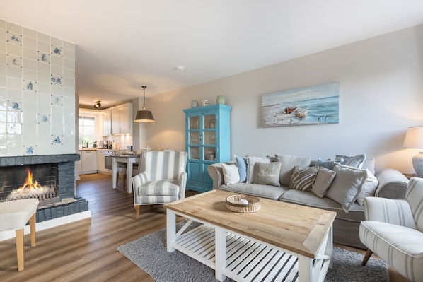 A cozy living room with a fireplace, a striped armchair, a blue cabinet, and a grey sofa.