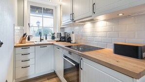 A modern kitchen with white cabinetry, a wooden countertop, and a built-in oven. - Ameland, App. 12 - Charme & Luxus Zwischen Dorfteich und Golfplatz (Wenningstedt-Braderup (Sylt))