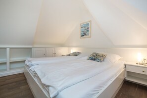 Ein Schlafzimmer mit einem großen Bett, einem Nachttisch, einem eingebauten Kleiderschrank und einem Dachfenster.