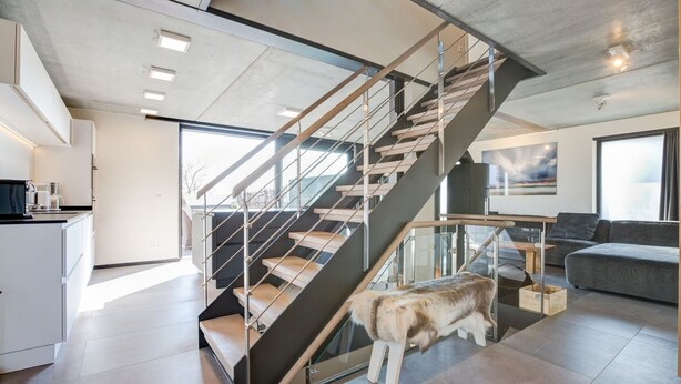 A modern interior with a staircase, a kitchen area, and a living space. - Willms Living, Long Beach House - Design-avantgarde. Viel Raum. Direkt an den Tinnumer Wiesen (Sylt)