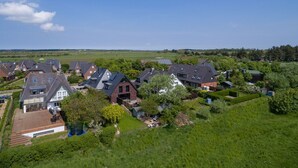 A residential area with houses, green lawns, and trees. - Willms Living, Sky - Design [&] Stil Pur. Raumwunder für Individualisten an den Tinnumer Wiesen (Sylt-Ost)