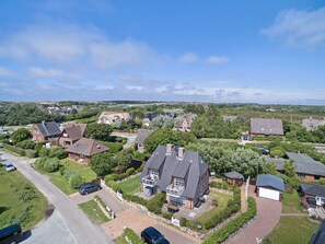 Et boligområde med huse, en hovedbygning med stor balkon og en indkørsel.