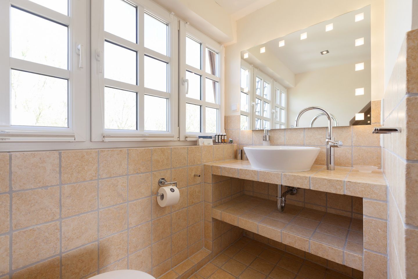 A bathroom with a large window, a sink, and a toilet.