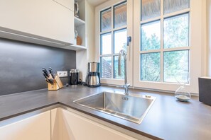 Uma cozinha moderna com uma pia de aço inoxidável, uma cafeteira e um porta-facas.