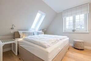 Une chambre à coucher comprenant un lit, une table de chevet, une fenêtre avec des stores et un radiateur.