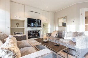 Un salon moderne avec un téléviseur à écran plat, une table basse et un canapé gris.