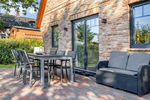 Une terrasse extérieure avec un mur en briques, une table avec des chaises et un canapé.