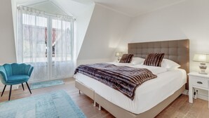 Una camera da letto con un letto grande, un comodino, una sedia e una finestra con tende.