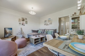 Un salon moderne avec un canapé, une table basse et une table à manger, le tout disposé pour un repas.