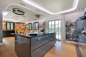 A modern kitchen with a central island, pendant lighting, and a mural on the wall.