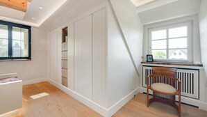Una stanza con soffitto spiovente, una panca integrata, un termosifone e una finestra con persiane.