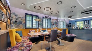 Un'area pranzo moderna con un tavolo in legno, sedie e una panca con cuscini colorati.