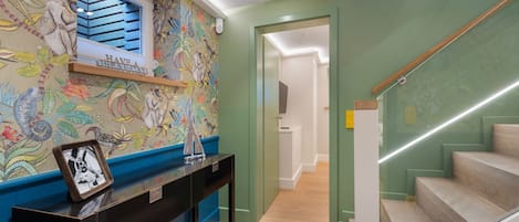 A hallway with a colorful mural, a console table with a framed photo, and a staircase with wooden steps.