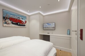 A bedroom with two beds, a TV, and a painting of a red car.