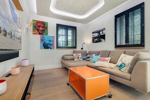 Una sala de estar moderna con un sofá, una mesa de centro naranja y obras de arte en las paredes.