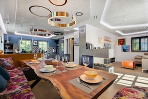 A modern kitchen with a dining area, a sofa, and a fireplace.