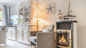 A cozy living room with a fireplace, a television, and a view of the outdoors.
