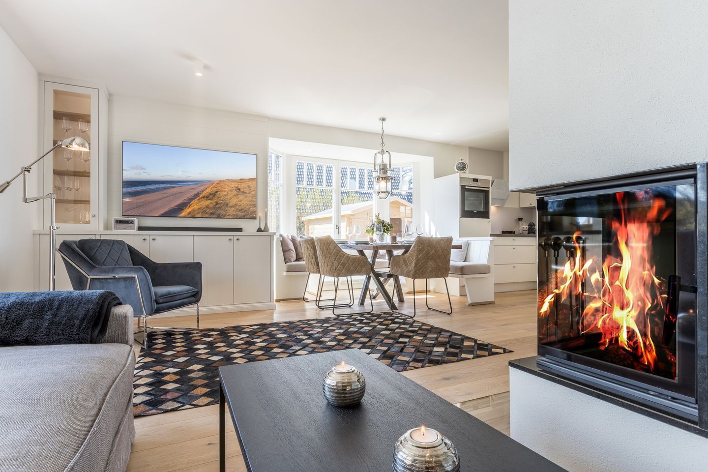 Ein modernes Wohnzimmer mit Kamin, Essbereich und Küche.