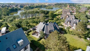 A residential area with houses, a river, and a truck parked in the driveway. - Haus Am Dorfteich, App. 2 - 2-raum-appartement im Erd- und Untergeschoss mit ca. 40m² Nutzfläche (Wenningstedt-Braderup (Sylt))