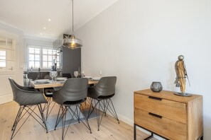 Un comedor moderno con una mesa de madera, sillas negras y una lámpara colgante.