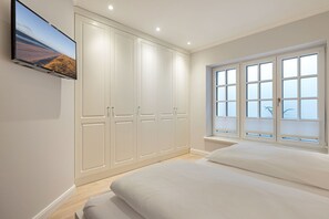 Un dormitorio con un armario grande, una cama y una ventana con persianas.