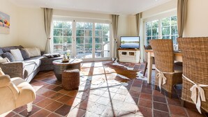 Un salon spacieux comprenant un canapé, une table basse et un coin repas avec des chaises en osier.