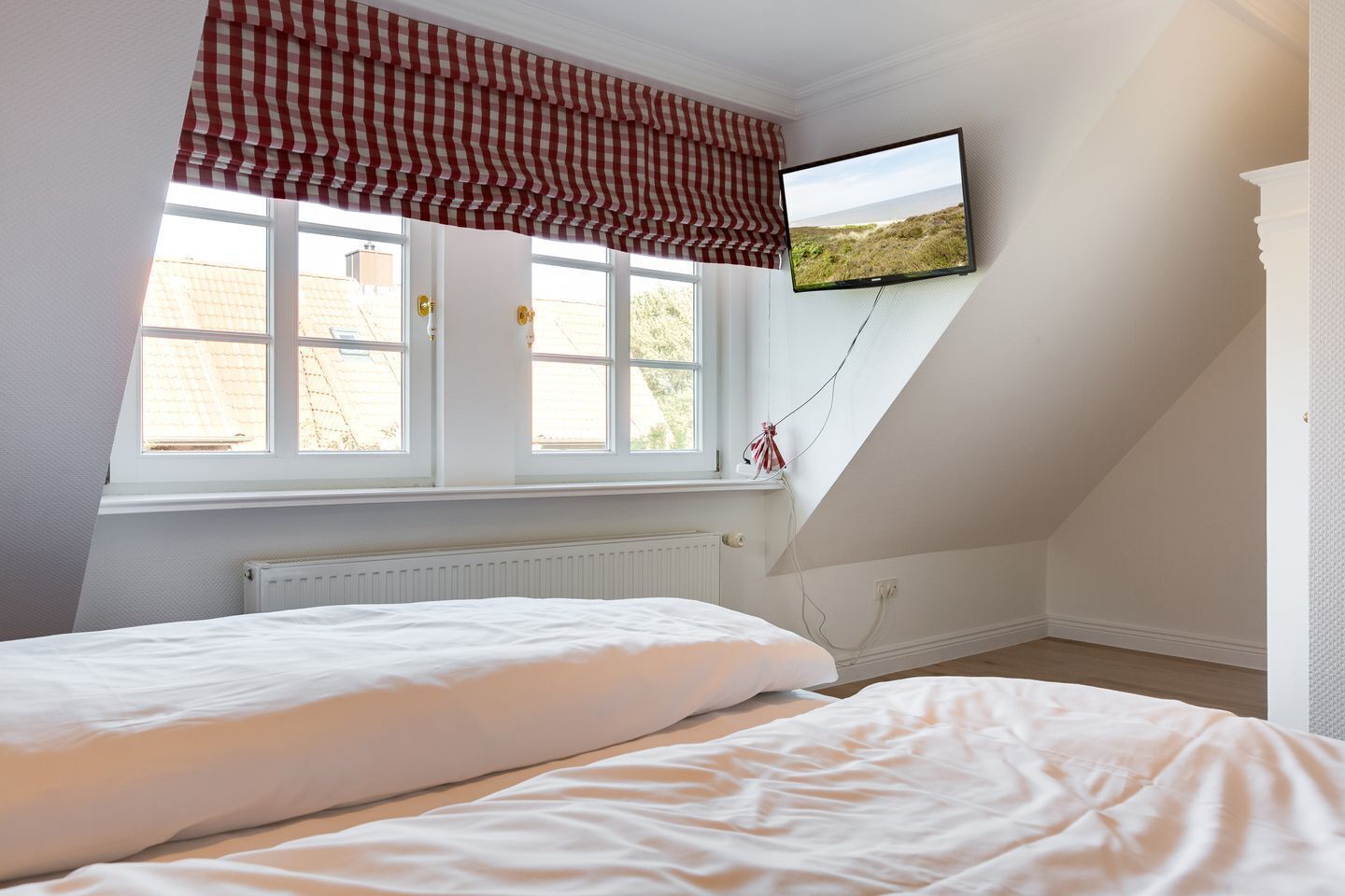 Une chambre avec deux lits, une fenêtre donnant sur un beau paysage et un téléviseur fixé au mur.