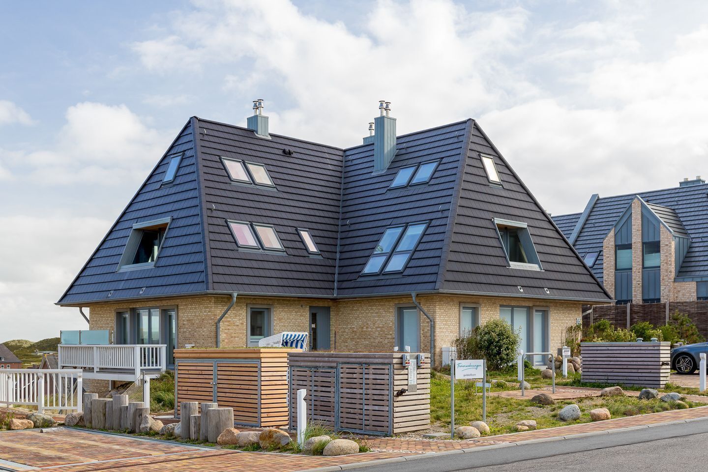A modern two-story house with a sloped roof, multiple skylights, and a brick facade.