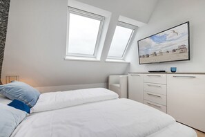 Een slaapkamer met een bed, een kaptafel en een schilderij van een strand.