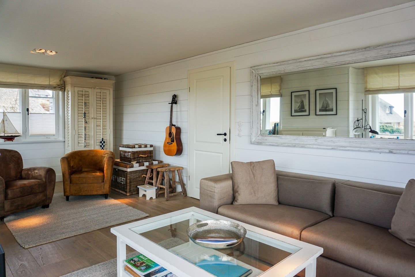 A cozy living room with a sofa, armchair, coffee table, and a guitar.