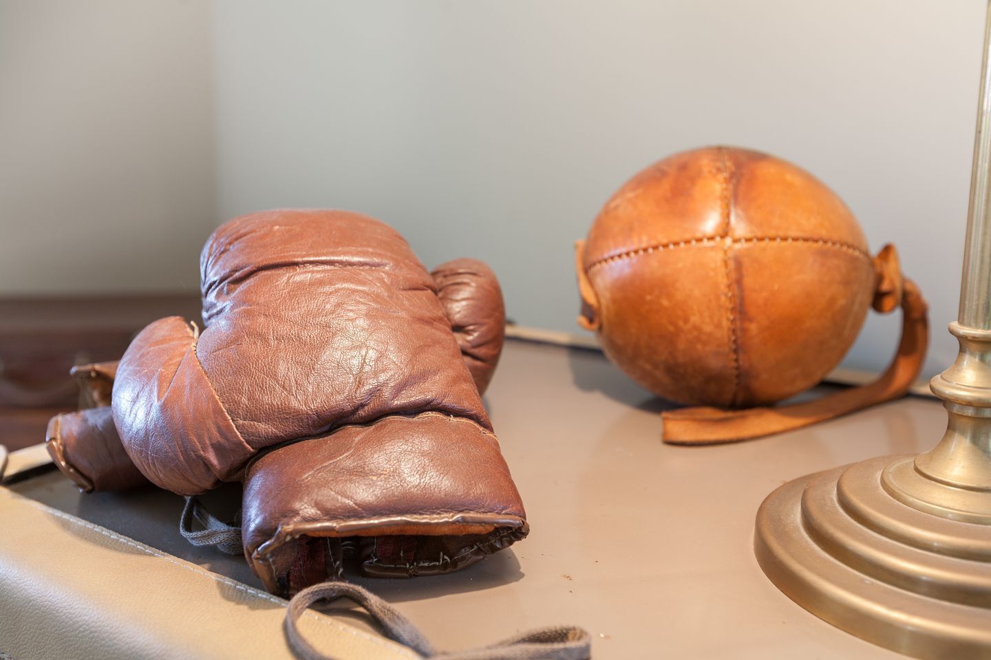 Un guanto di pelle marrone e un pallone di cuoio su un tavolo.