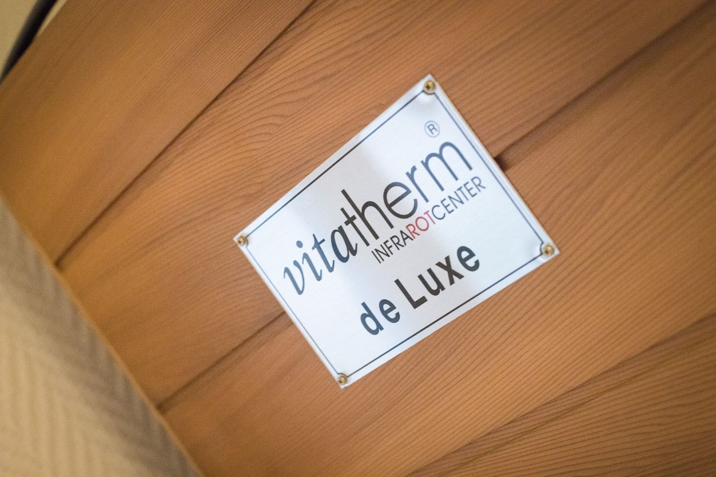 A sign on a wooden floor with the text "vitatherm INFRAROTCENTER de Luxe".