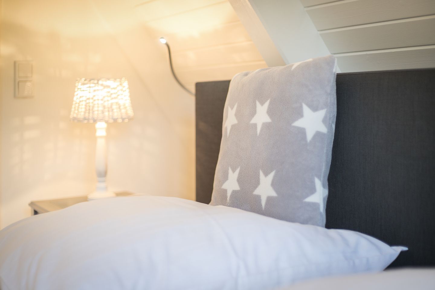 A hotel room with a bed, a nightstand, and a lamp.