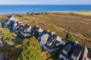 Un quartier résidentiel situé sur la côte, où les maisons sont alignées le long d’une route et offrent une vue sur la mer.