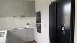 A modern kitchen with grey cabinets, a black refrigerator, and a wooden floor. - Rural Setting - Close to shops, Townsville Hospital and Riverway (Gumlow)