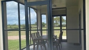 A modern patio area with a sliding glass door leading to a grassy outdoor space. - Rural Setting - Close to shops, Townsville Hospital and Riverway (Gumlow)