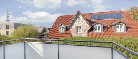 A residential building with a red-tiled roof, a stone facade, and a small window.