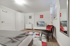 A bedroom with a bed, a chair, a dresser, a TV, and a mirror. - Hüs Moinsen - In Ruhe die Zeit mit der Familie Genießen? Das Hüs Moinsen ist der Richtige Ort (Sylt)