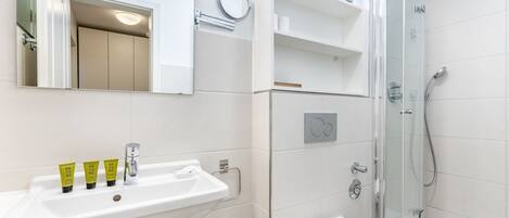 Ein modernes Badezimmer mit einem weißen Waschbecken, Spiegel und einer Duschkabine.