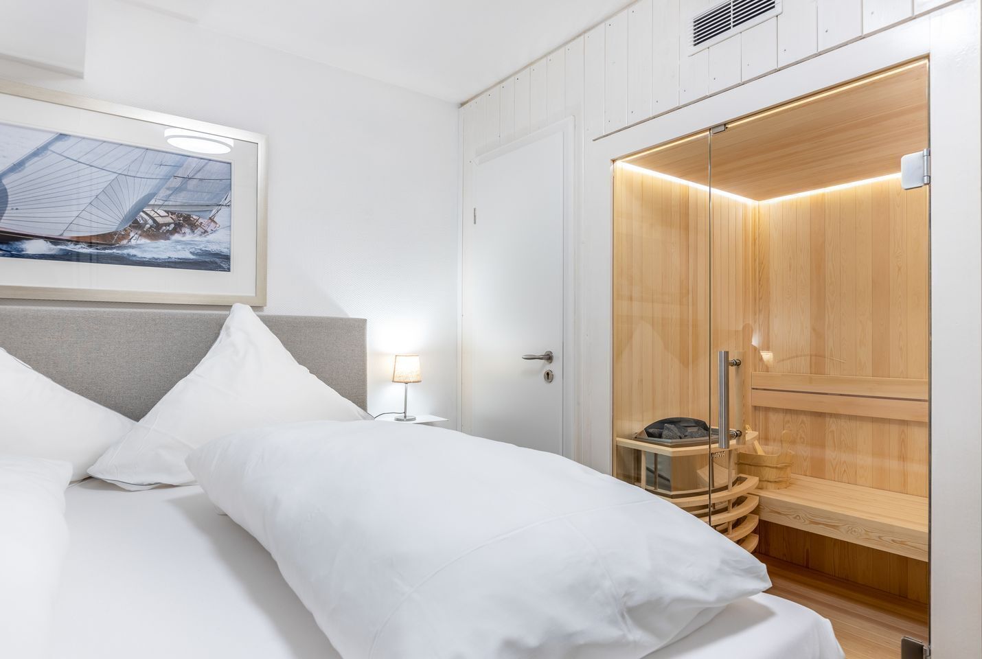 A hotel room with a bed, a nightstand, a wooden sauna, and a framed picture on the wall.