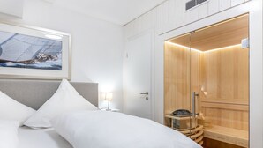 A hotel room with a bed, a nightstand, a wooden sauna, and a framed picture on the wall. - Ringelgans - Urlaub im Herzen von Westerland, das Erleben Sie in dem Appartement Ringelgans (Sylt)
