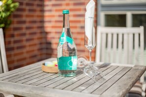 A bottle of Sylter Aqua on a wooden table with a glass and a napkin. - Inselsuite - Beste Lage. Beste Ausstattung. Bester Urlaub (Sylt)