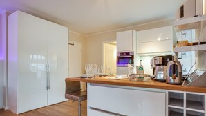 Une cuisine moderne avec des meubles blancs, un plan de travail en bois et une machine à café.