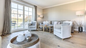 Un salon spacieux doté d’une grande fenêtre, d’un ensemble de canapés, d’une table basse et d’un panier décoratif.