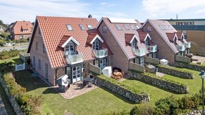 A modern residential building with a red-tiled roof, multiple balconies, and a well-maintained lawn. - Dünen & Meer, App. 2 Dünen-nest - In Strandnaher und Dennoch Zentraler Lage Gelegenes 3-raum (Sylt)